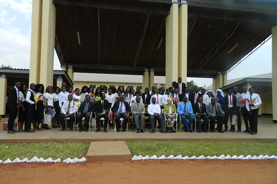 Graduated teachers in a group photo with guests