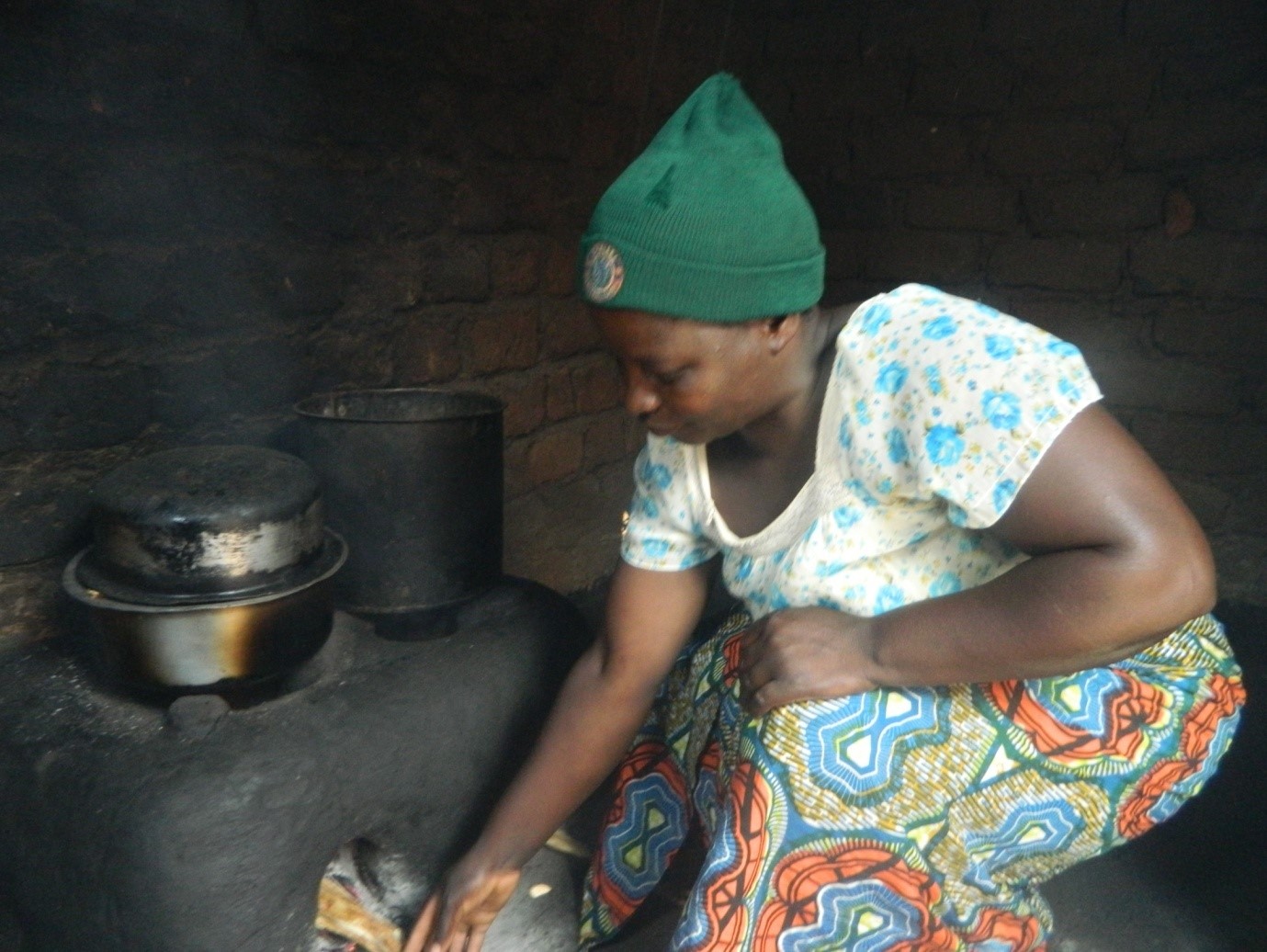 Doreen inserts a piece of firewood into a firewood savingstove in her kitchen