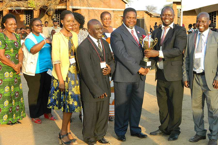 An outsanding headteacher receives a trophy from the minister