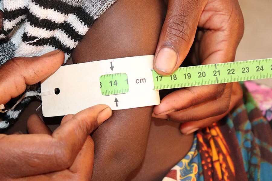 A mother uses the MUAC tape to record her childs nutrition status